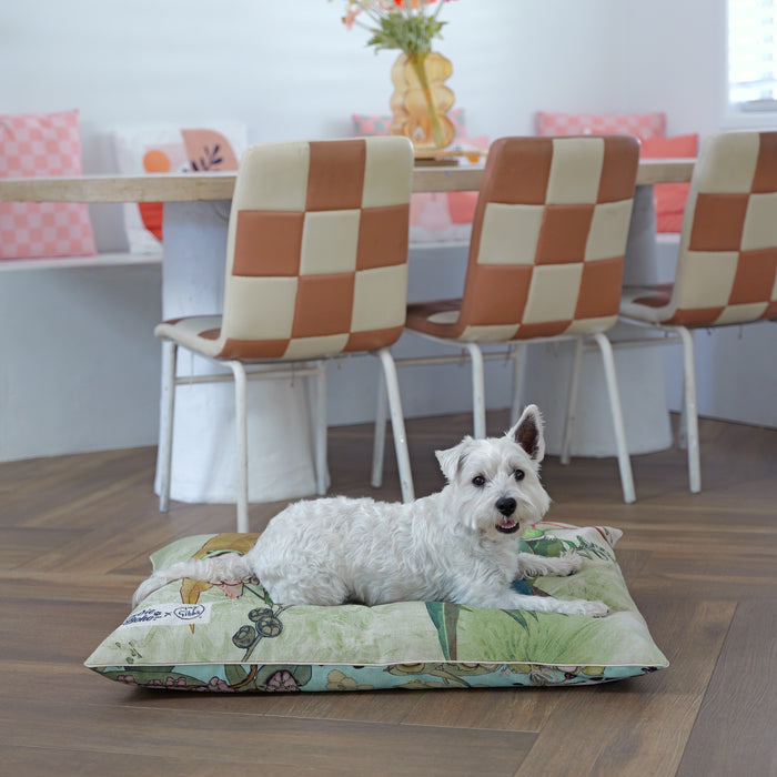 Happy west highland terrier lying on a May Gibbs dog cat and pet bed with a gumnut babies earthy green design, reversible bed cover