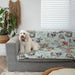 cute white bordoodle sitting on a blue may gibbs couch cover couch throw with colourful gumnut babies design