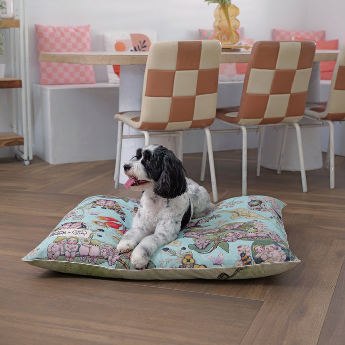 Happy cavoodle sitting on a large dog bed showing soft blue May Gibbs bush babies and gumnut babies design, with linen blend reversible pet bed for cats and dogs