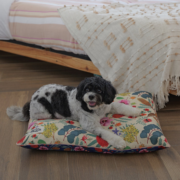 Native flora dog bed, happy cavoodle lying on a small dog bed with an Australian plants and flower design in yellow and blue
