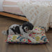Native flora dog bed, happy cavoodle lying on a small dog bed with an Australian plants and flower design in yellow and blue